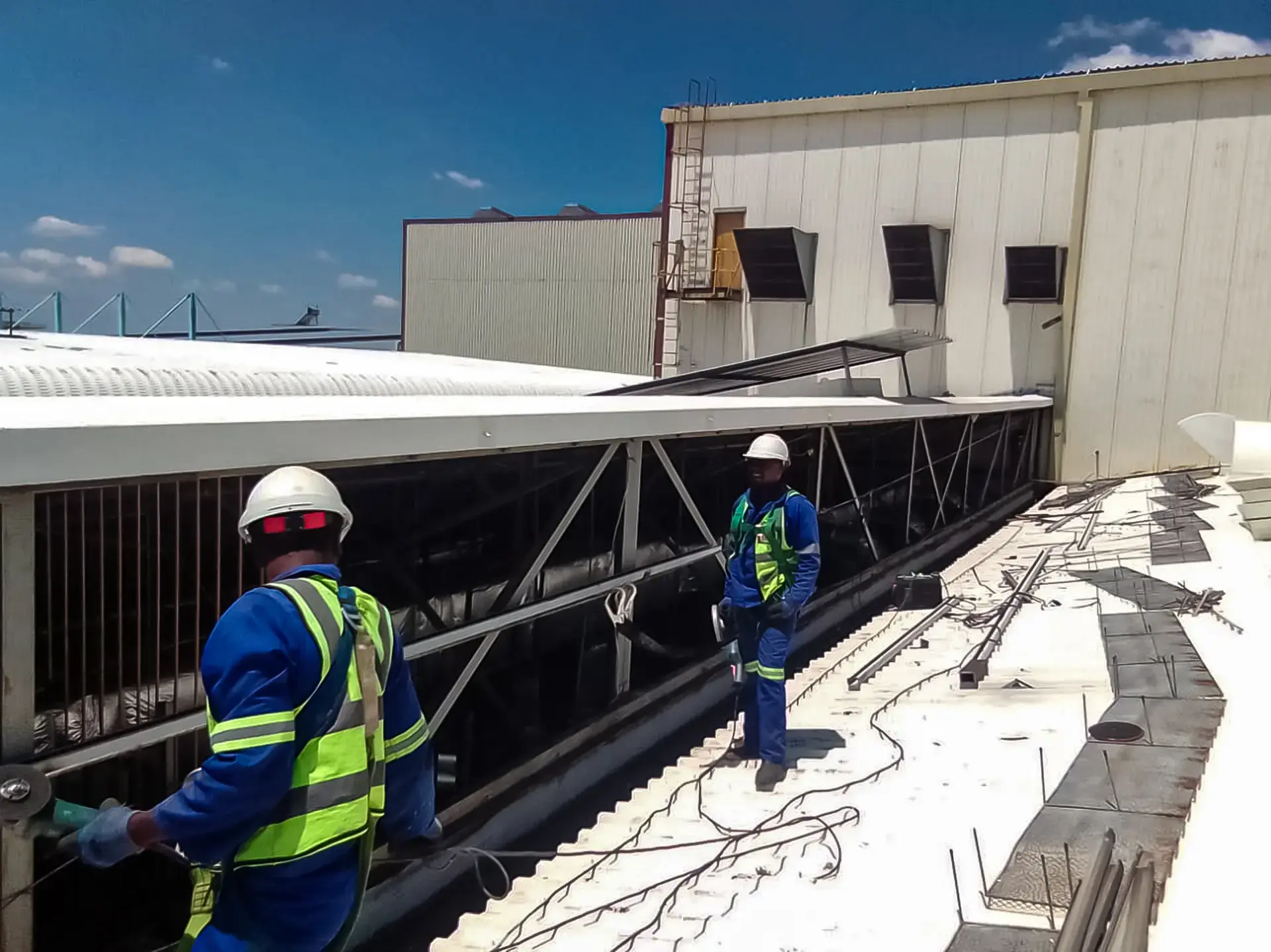 Skilled workers in safety gear performing detailed roof installation on a commercial building, providing quality service near you.